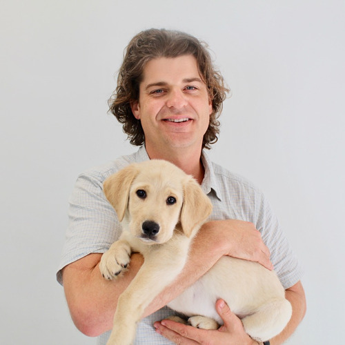A photo of Brian Hare holding a golden lab puppy.  