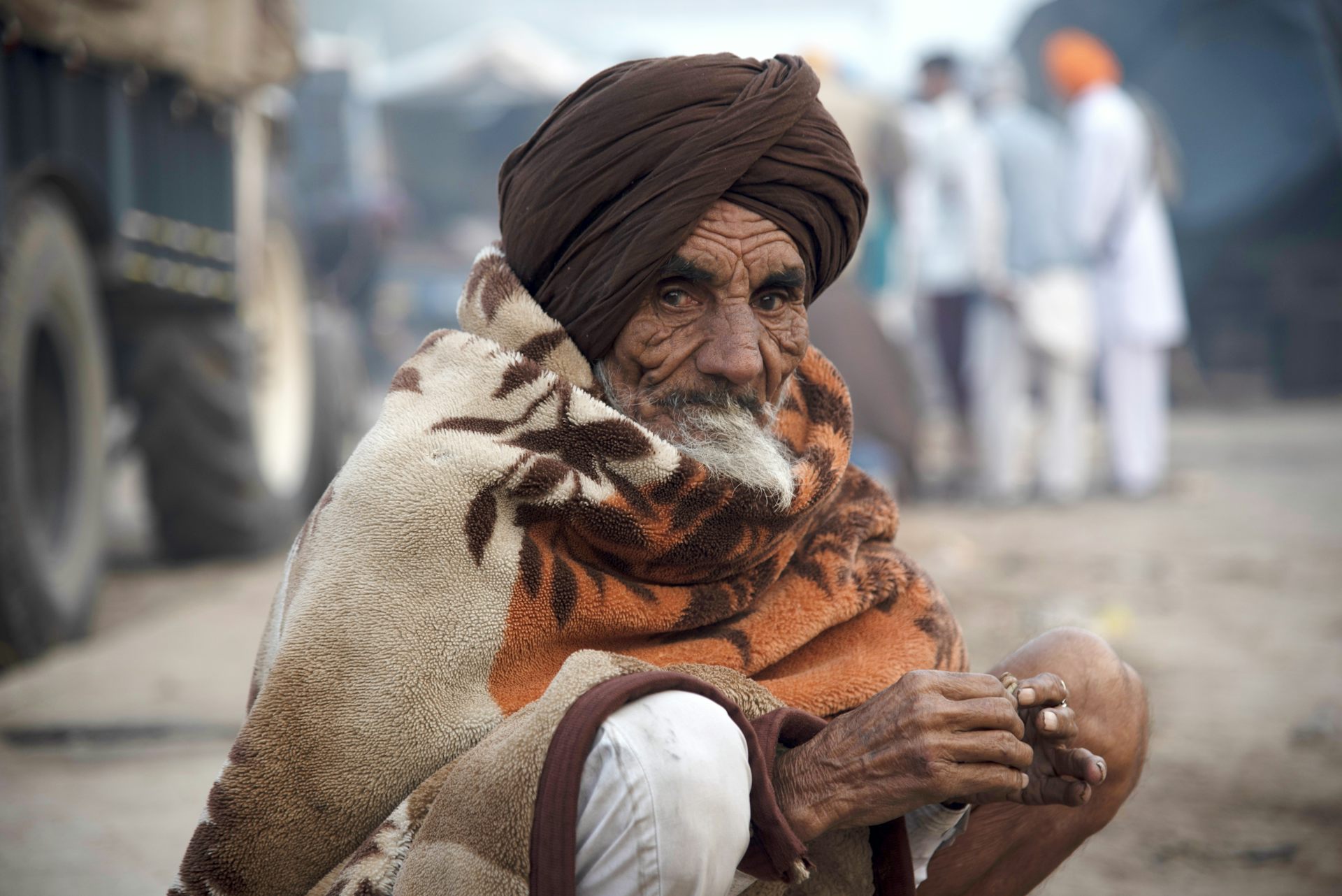 a squatting old man with weathered skin