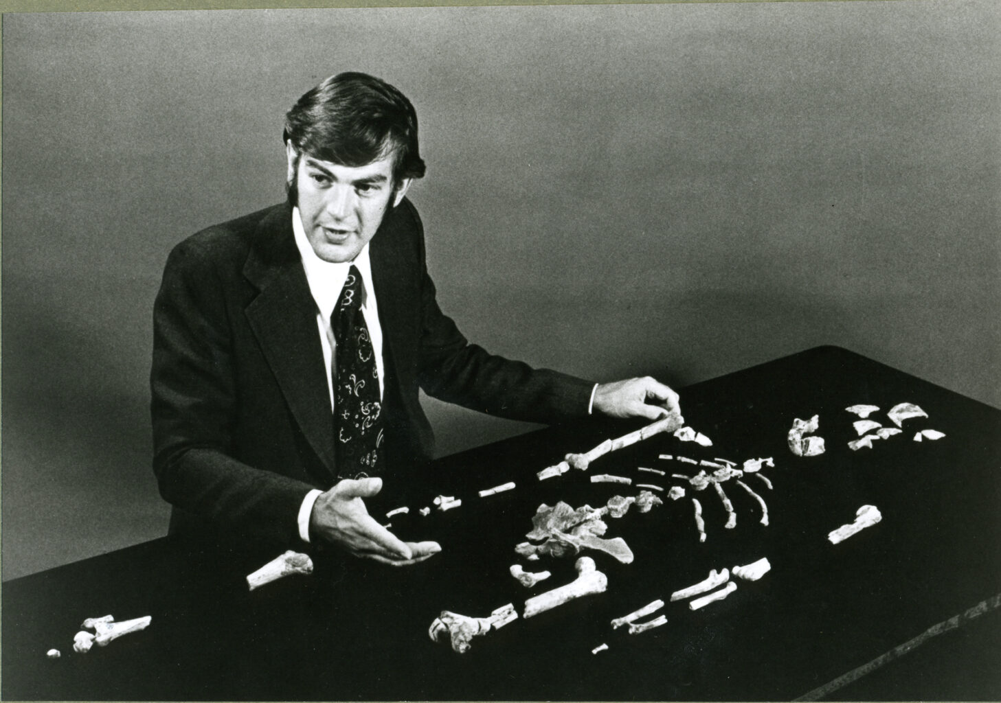 Black and white photo of Don Johanson with the fossilized remains of Lucy.