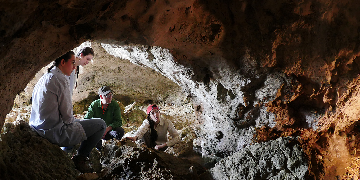 A group of scientists in the opening of a small cave.