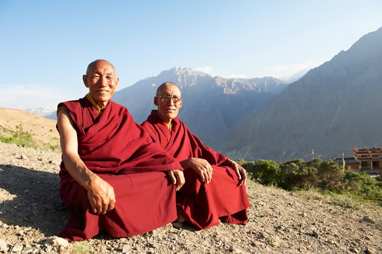 Two Tibetan monks sitting in the mountains