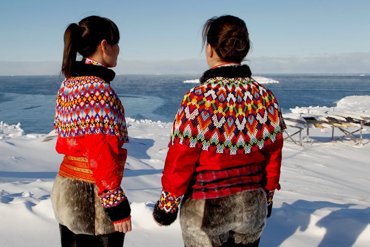 Two Inuit women looking out to sea