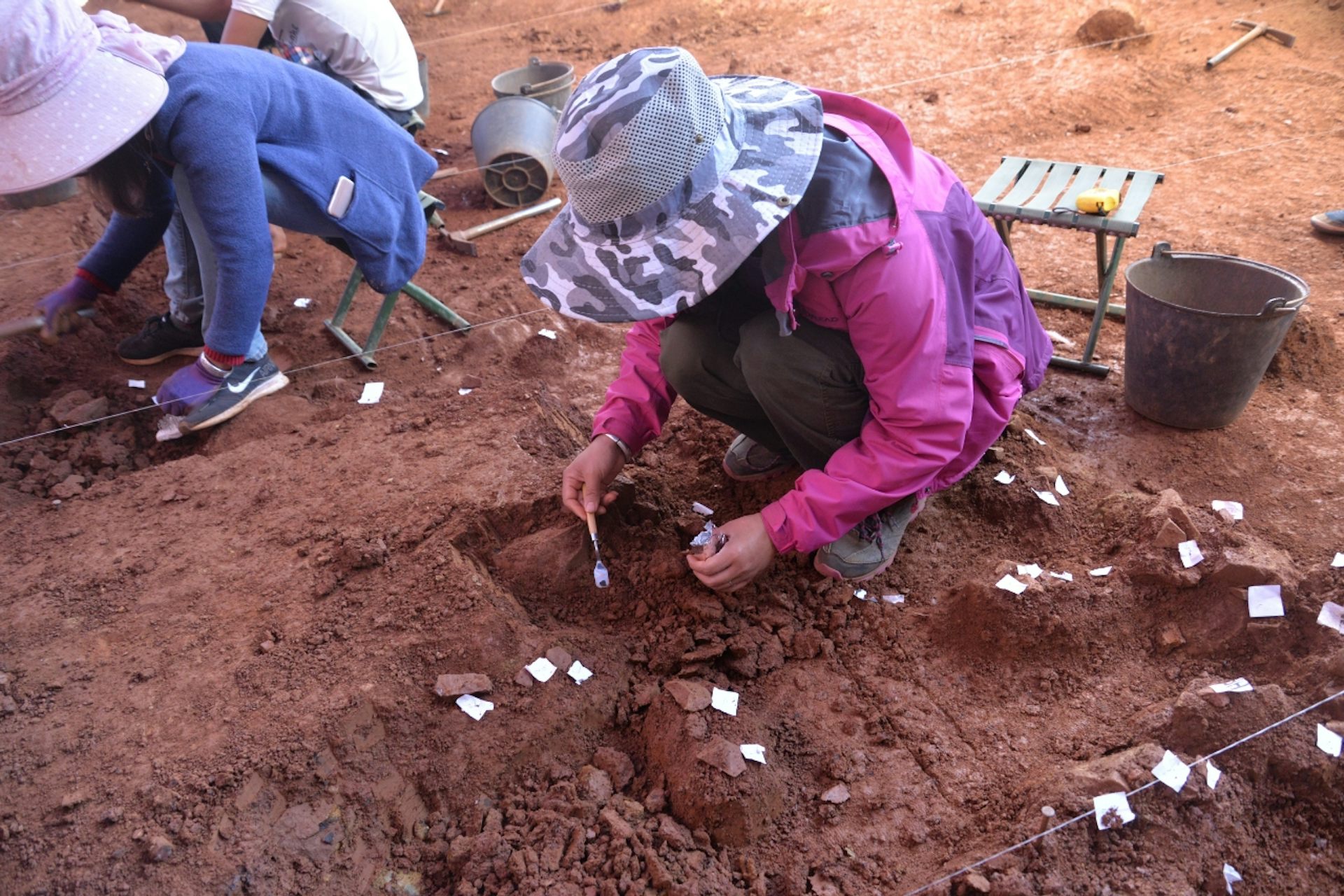 Archaeologists looking down and focused on excavating stone tools at Longtan in China.
