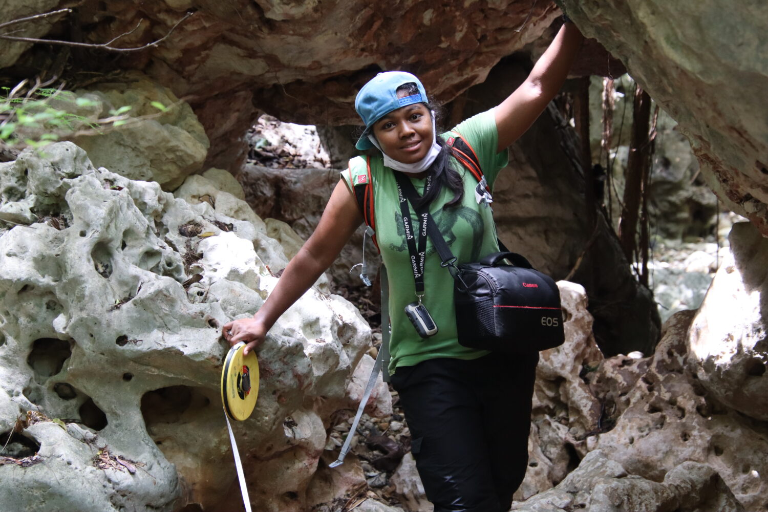Eva Stela Nomenjanahary standing in front of rocks setting a transect line in the New Protected Area, Ambohitr'Antsingy, Montagne des Français, Madagascar.