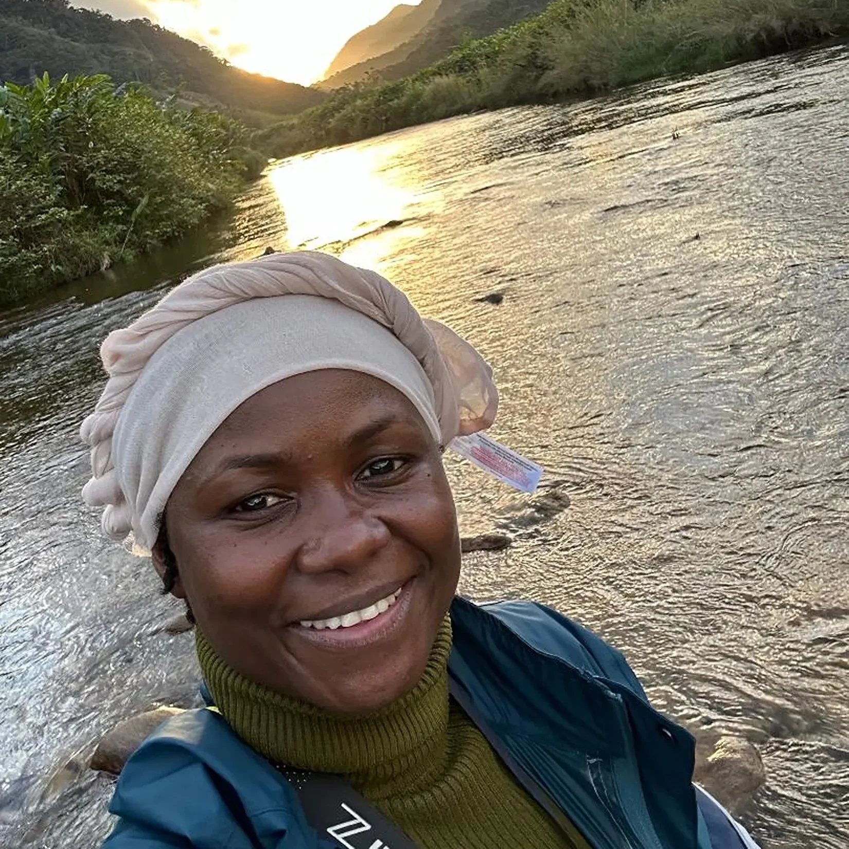 Florence Aghomo in the field with a sunset view of Ranomafana National Park behind her.